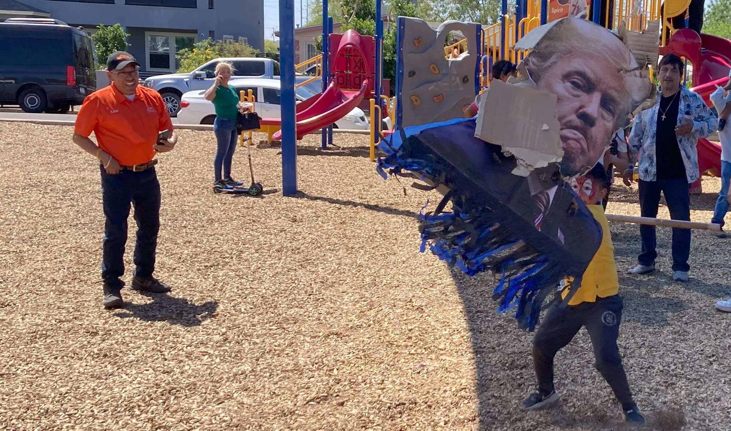 a kid in spider-man face paint bashes a donald trump pinata
