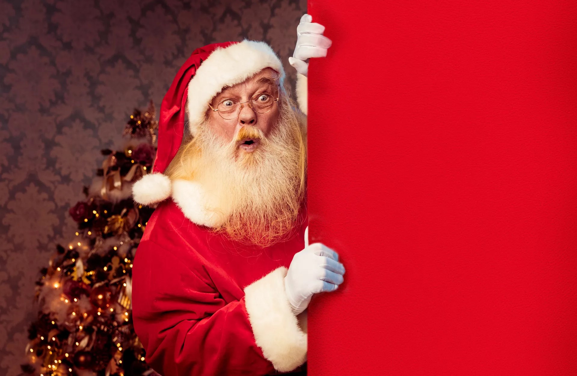 a shocked santa peeks around a corner