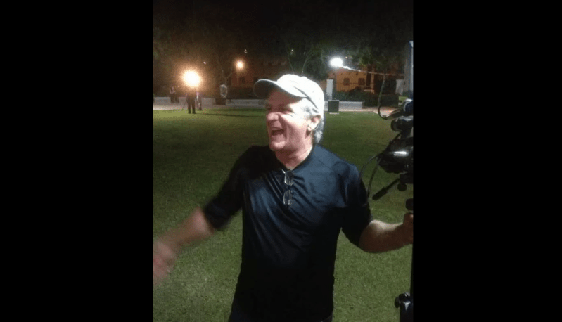 a man smiles at night holding a video camera