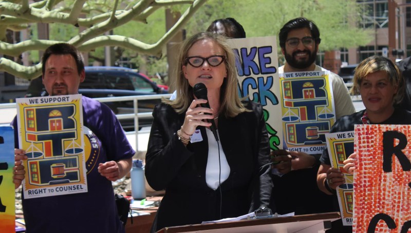 a woman in glasses speaks at a protest