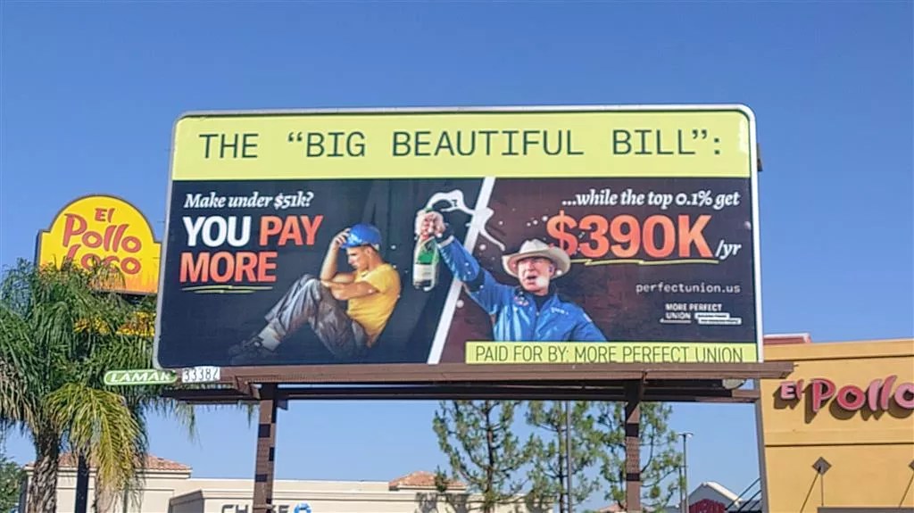 A billboard that features a despondent blue-collar worker and a celebratory Jeff Bezos. "Make under $51K? You pay more," it says, "while the top 0.1% get $390K/yr"