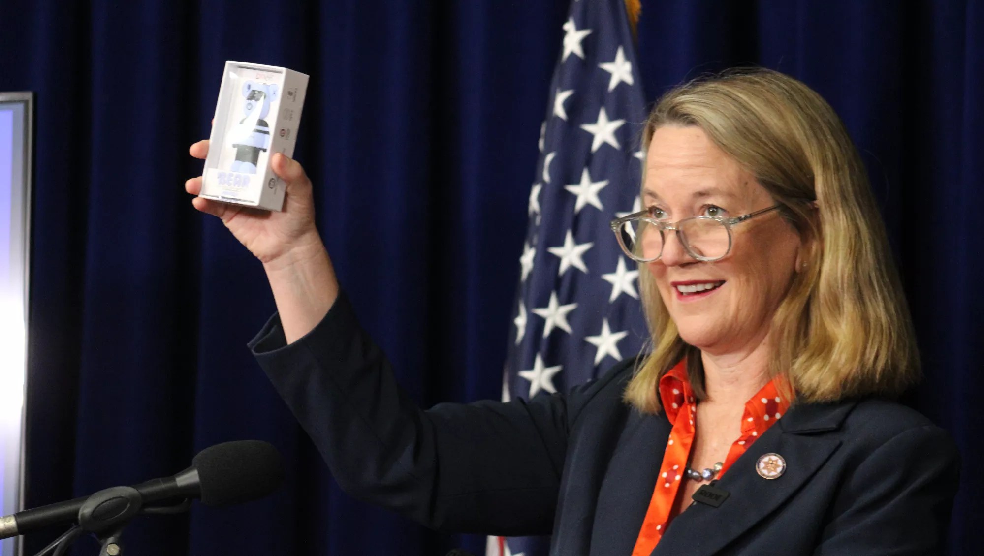 kris mayes holds up a vape cartridge at a press conference
