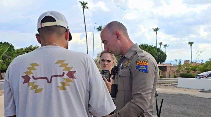 an Arizona Department of Public Safety trooper speaks to a man in a white shirt and hat
