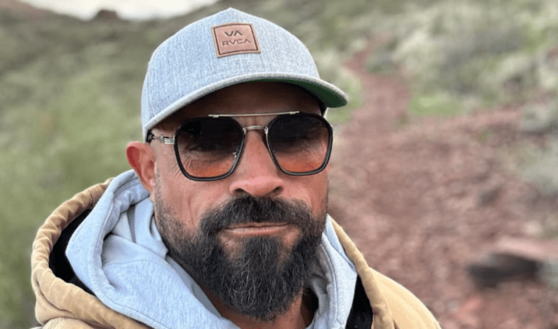 a man in a hat and sunglasses outside