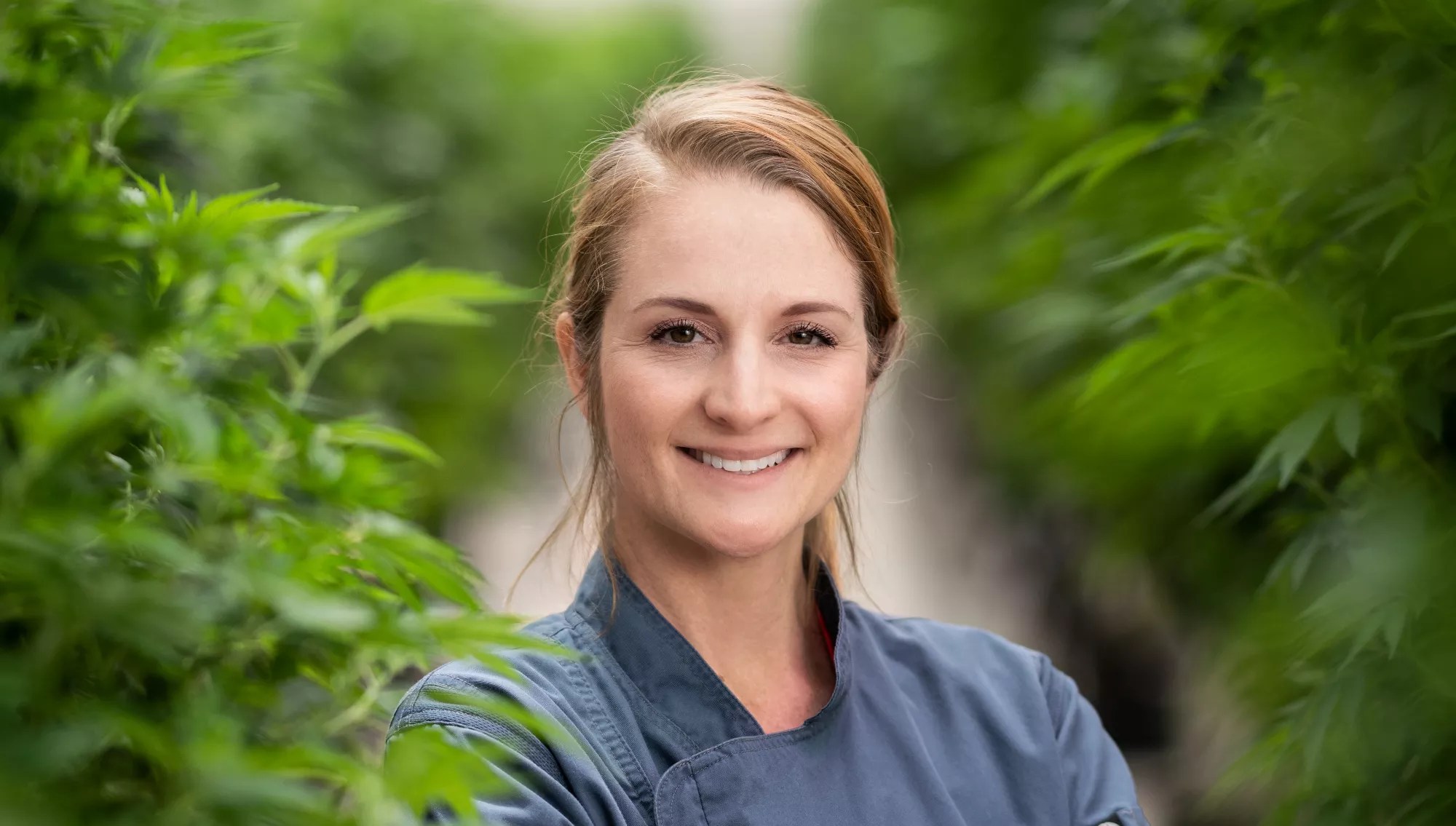 a woman in front of rows of marijuana plants