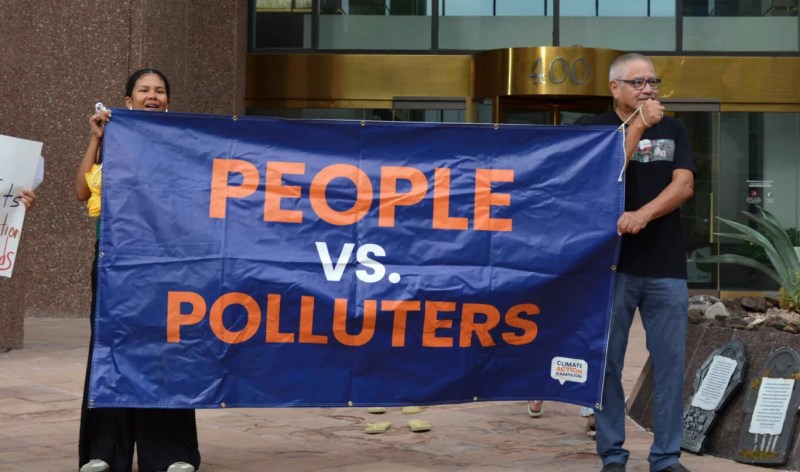 Protesters stand outside of Arizona Power Service’s headquarters on Thursday after the utility’s recent decision to walk back its clean energy goals.