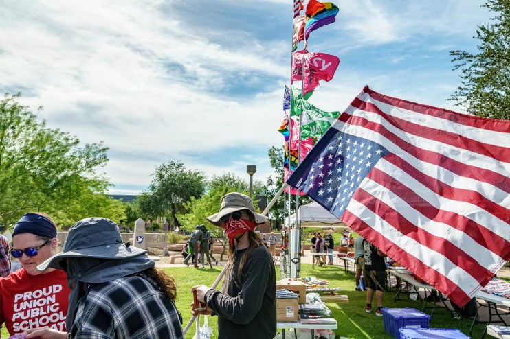 a protester with his face covered by a bandana holding up an upside-down U.S. flag
