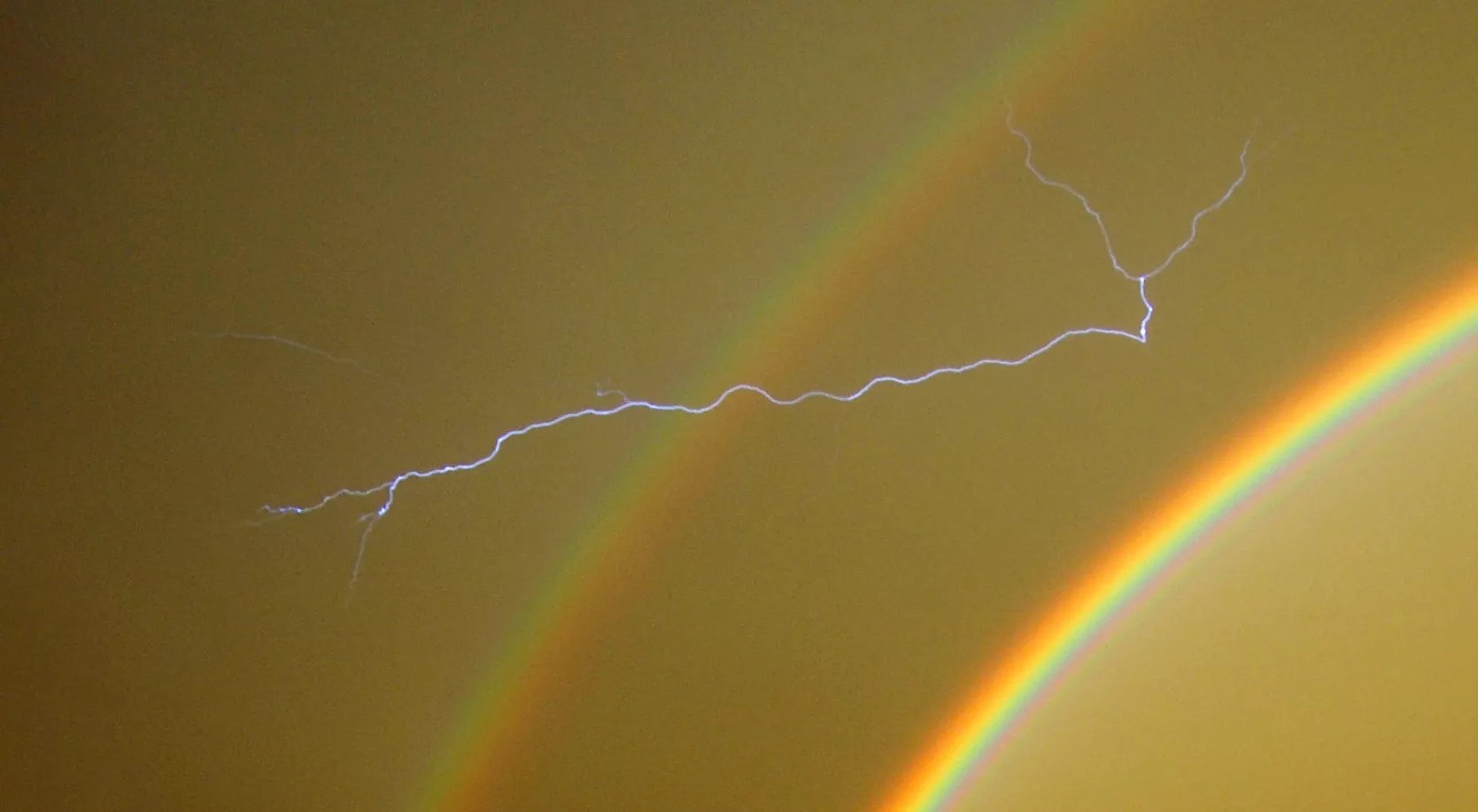 a lightning bolt streaks across a rainbow